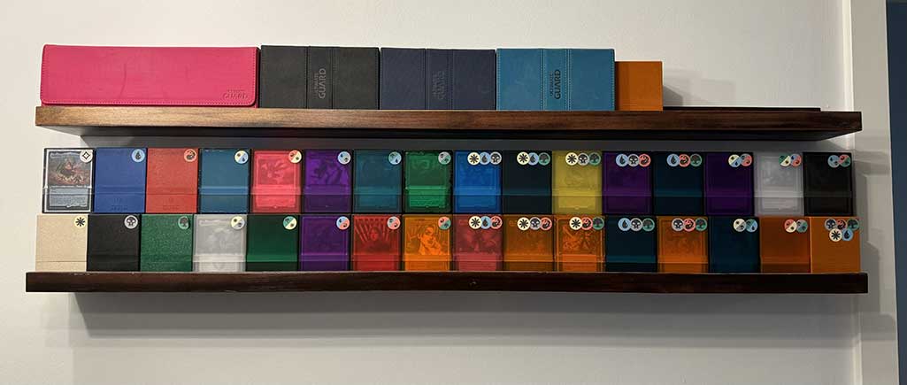 My shelves of Magic supplies and 32 Commander Magic: The Gathering decks that correspond to each available color identity.