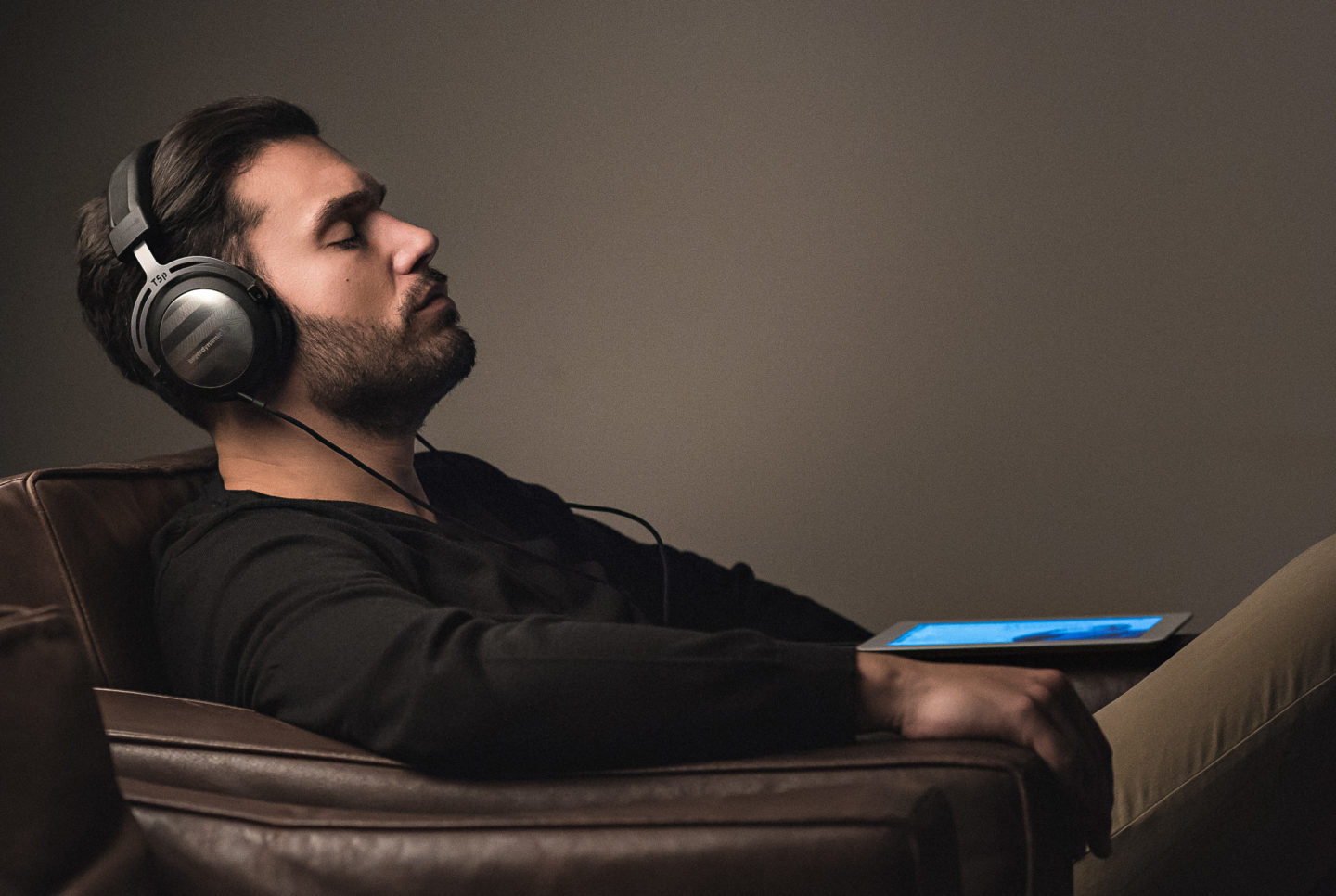 Guy listening to wired headphones on a couch