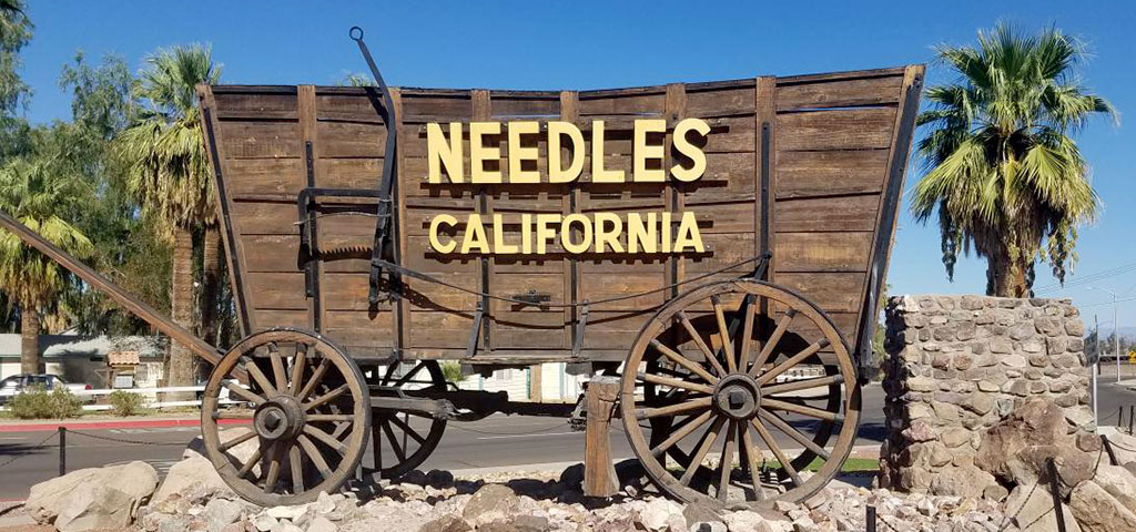 An old wooden wagon replica with Needles California written on it