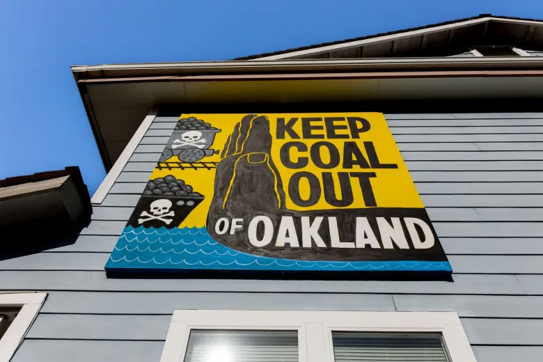 A handmade sign on the side of a building reads Keep Coal Out of Oakland