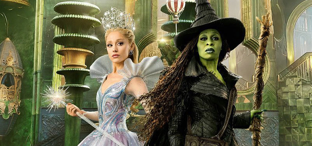 Glinda and Elphie from Wicked: For Good posing in front of Oz as a backdrop